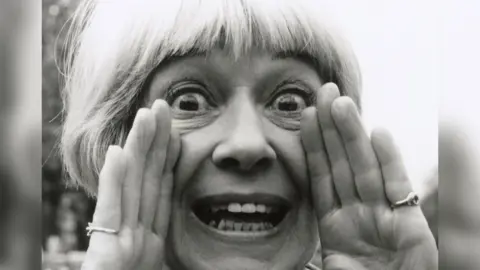 Jackie Forster, pictured in 1996 cupping her hands round her mouth 