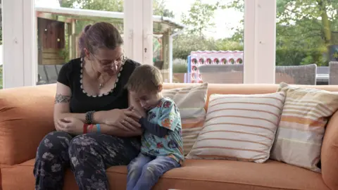 Michaela Middleton Michaela Middleton sat on the sofa staring down at her son Finley who is hugging on to her arm.