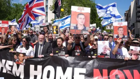 PA Media People holding banners, placards and images of hostages at the United We Bring Them Home march in London