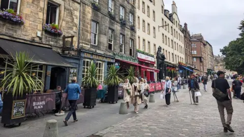 A cobbled and pedestrianised street with pubs and restaurants on one side.