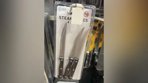 A pack of four steak knives on display in a shop, but the pack has been opened and one of the knives is missing. 
