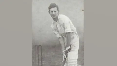 Essex Cricket Club A black and white photo of Claude Ashton, in his cricket whites in a batting position, leaning over and holding a bat. A wicket can be seen on his right. He has short dark hair.