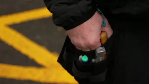 Close-up shot of hand in toolbelt. Tools can be seen in the black toolbelt. 