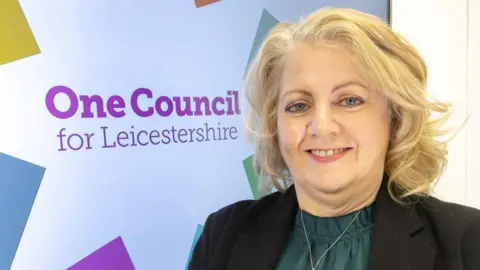 Leicestershire County Council Deborah Taylor standing next to new council branding