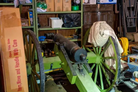 RCMP An antique cannon is seen in a storage area with shelving units and other boxes and miscellaneous items in a home in Dauphin, Manitoba.