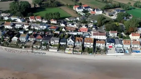 BBC An aerial view of Jersey showing a part of a beach and some houses.