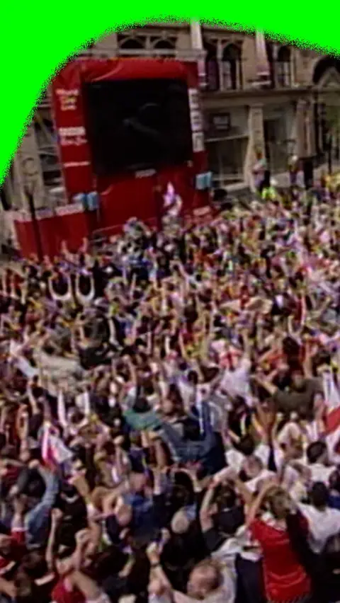 A crowd in Manchester chearing at a big screen as England beat Argentina in the 2002 World Cup.
