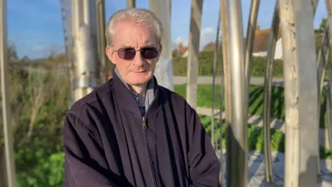 Anthony Mallinson - a man with sunglasses, grey hair and a black jacket