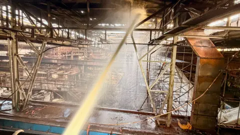 Mid and West Wales Fire and Rescue Service a fire hose shoot into a tangle of metal in a high building 