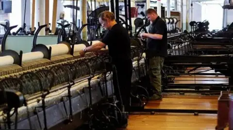 Staff work on the looms at Helmshore Mills Museum