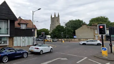 Google Street view of junction between West Street and Victoria Avenue in Southend. Two cars - one white and one dark blue are waiting for the traffic lights to change colour and a white car is crossing on the road ahead