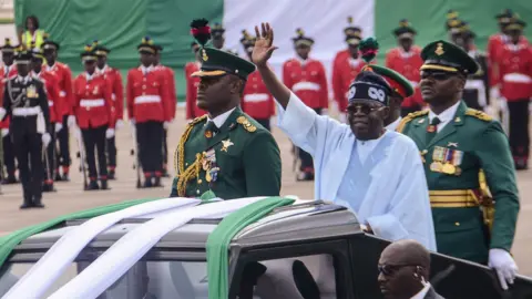 Nigeria President Bola Tinubu in a white robe waves his hands during a presidential parade at Eagles square, Abuja - 2024