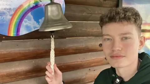 A teenager rings a "cancer free" bell at the Nottingham Teenager Cancer Trust Unit