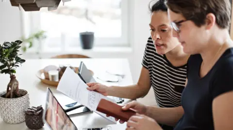 Getty images two women sit at the desk and see a bill.