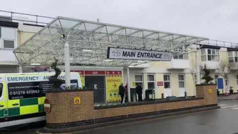 The main entrance to a hospital A&E department with an ambulance parked outside