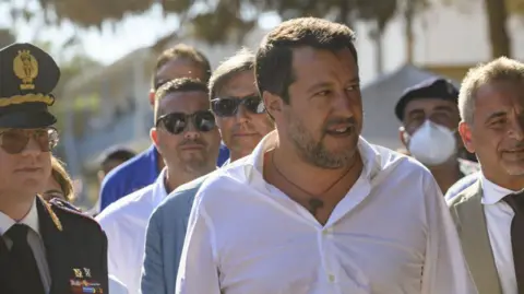 Getty Images Italy's deputy prime minister is surrounded by officials as he visits the Italian island of Lampedusa in 2022