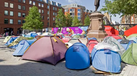 Getty Images View of tents in the centre of Manchester UK used by the homeless. People can be seen on the promenade.