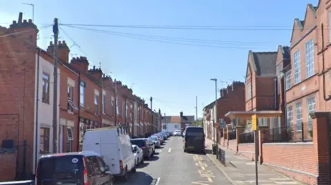 Parked cars on street with terraced houses.