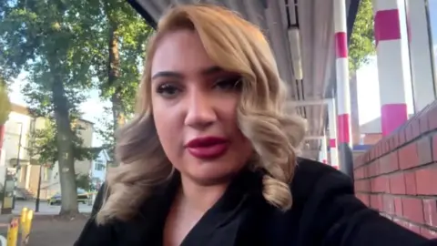 A woman with blond hair and a black top looking directly at the camera.