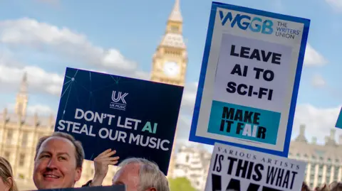 Creatives in the music industry protest outside UK Parliament. A dark blue placard from trade association UK Music reads: "Don't let AI steal our music". Another beside it, from The Writer's Union, says: "Leave AI to sci-fi". 
