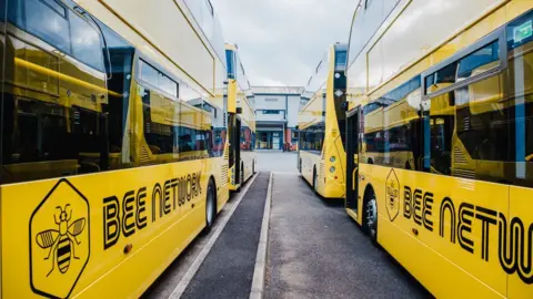 Yellow buses lined up at a bus depot in Greater Manchester.