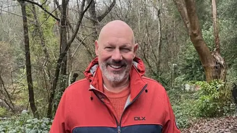 Roger Barton, Treasurer for FTWRC, standing in woodland at Still Green, Rusthall