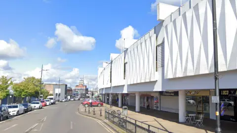 A generic view along Cleveland Street with the white market building on the right and cars parked down one side.