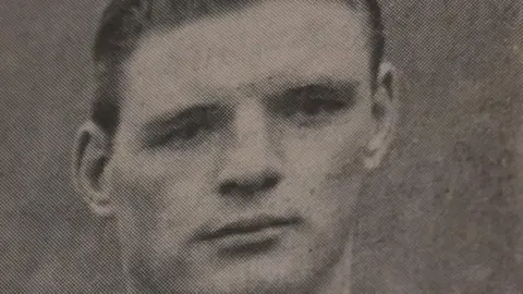 Barnsley Council An old black‑and‑white photograph printed on textured paper. Mark Jones' hair is neatly styled and brushed back. The background is plain and slightly grainy.