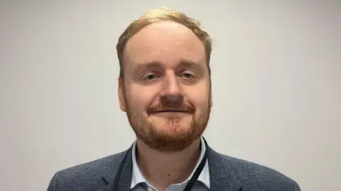 BBC/Laura Coffey Adam Brown with short brown hair and beard