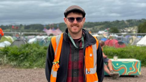 Man stood in high-vis jacket at the top of Glastonbury Festival site 