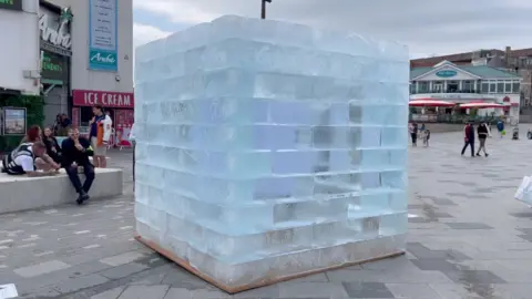 A large block of ice next to a building.