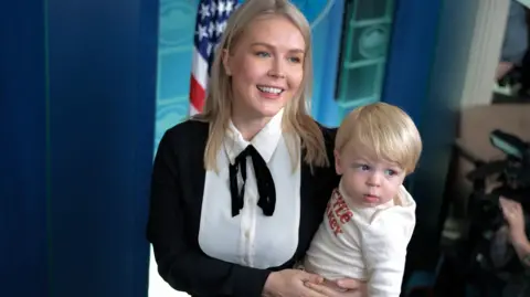White House Press Secretary Karoline Leavitt holds her son in the press briefing room of the White House
