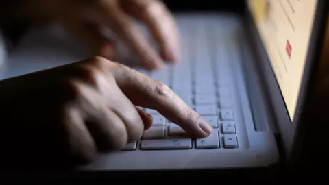 Two hands on a white laptop keyboard. The screen is blurred.