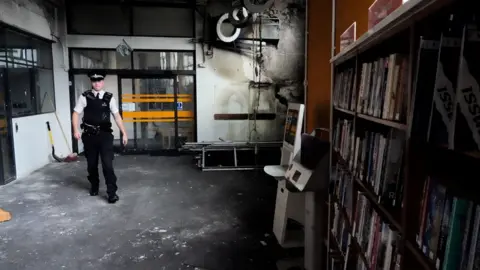 Reuters A police officer walks inside the Spellow Library after it was targeted and damaged by rioters