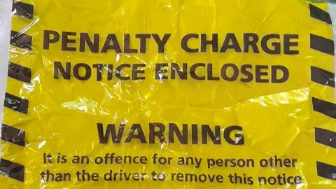 ASA A yellow and black parking ticket which says PENALTY CHARGE NOTICE ENCLOSED.