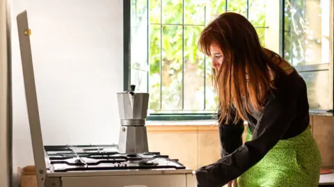 Woman making coffee on a gas cooker