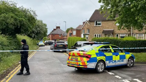 A police car behind a cordon in a residential road