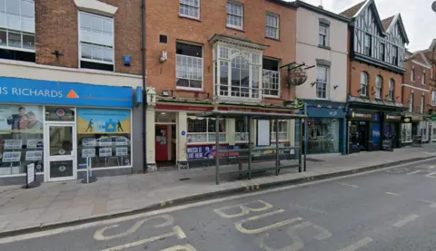 Google A view of the Golden Ball pub from the High Street in Bridgwater. The pub has red signs and a red door with beige walls.