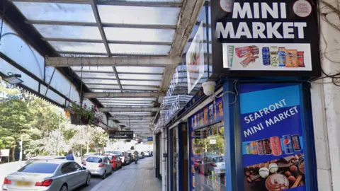 Shopfront on road lined with parked cars