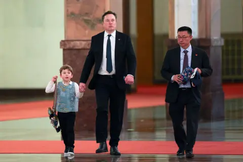 EPA Tesla CEO Elon Musk (C) and his son X Æ A-12 (L) walk ahead of a meeting between Chinese Premier Li Qiang (not pictured) and American CEOs, in Beijing, China, 14 May 2026.