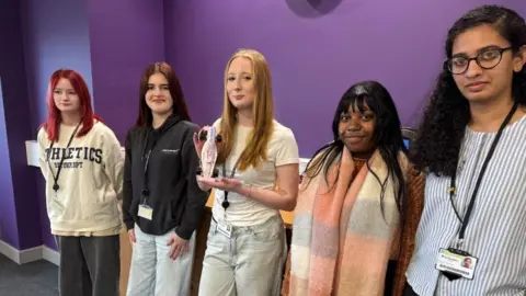 Five girls standing next to each other, smiling at the camera.