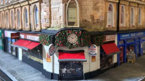 A cardboard model of Union Corner. It is a Victorian Building with colourful shop fronts on the ground floor.