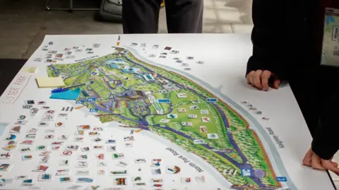 Born in Bradford A map of Lister Park in Bradford with printed icons around it. A young person leans over it