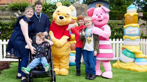 Family standing with Winnie the Pooh and Piglet