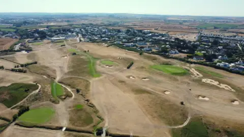 An aerial shot of a golf course in Cornwall showing very dry, brown areas of grass