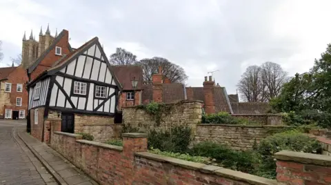 Heritage Lincolnshire The Tudor-style building, known as the Wonky House, leaning to the right. Lincoln Cathedral can be seen in the background.