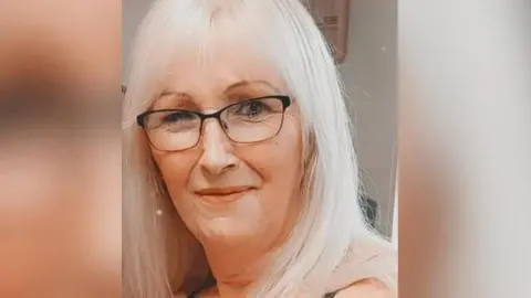 A head and shoulders photo of Milly Rosevear who has long blonde hair and is wearing glasses and smiling at the camera.