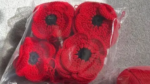 Westbury Yarn Bombers/Veronica Lottering Red knitted poppies in a bag