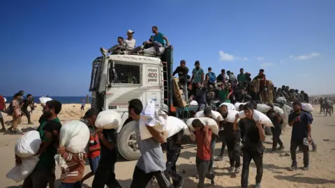 Reuters Image shows Palestinians carrying aid supplies in Beit Lahia, northern Gaza, on 20 July, 2025