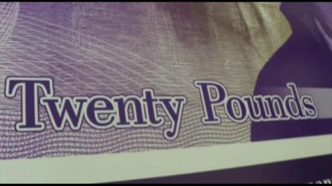 A close up of the words "Twenty Pounds" written on an old purple £20 note.